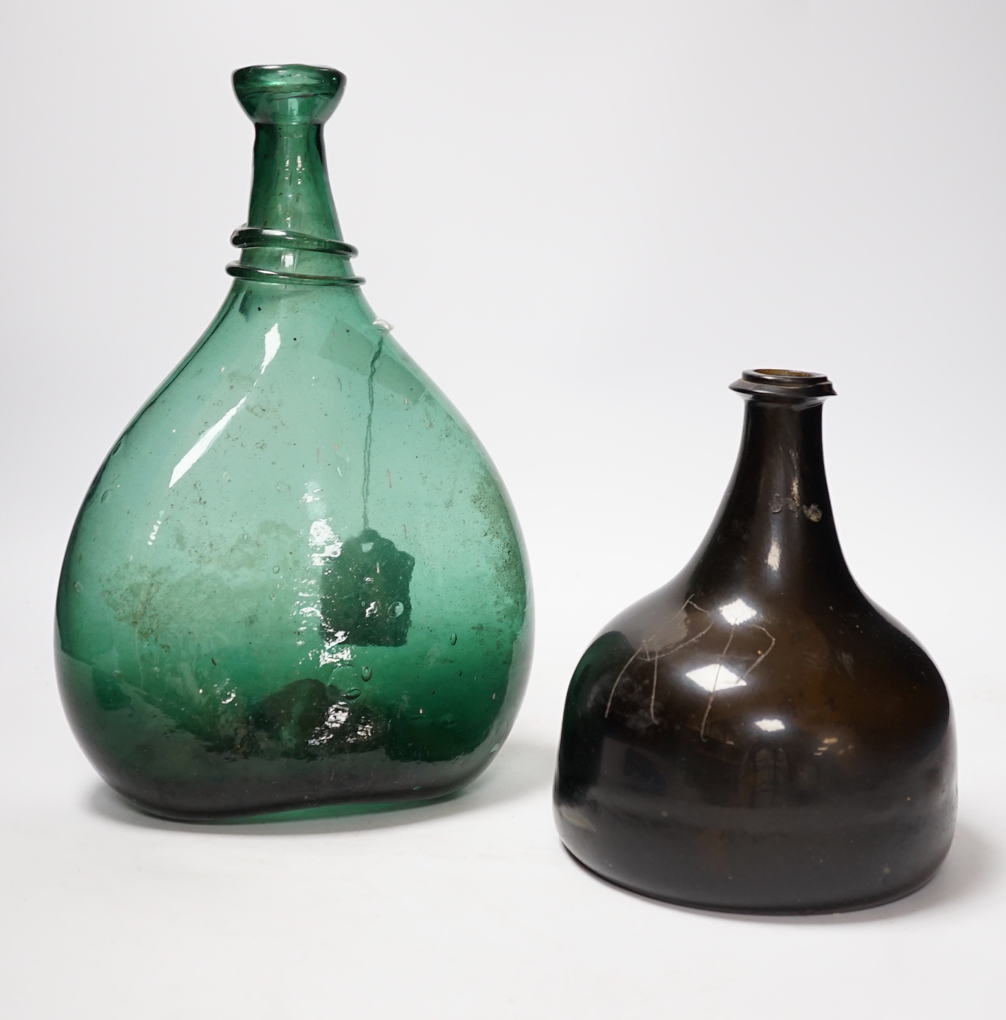 An 18th century black glass mallet form bottle with neck rim, 17cm and an 18th century Persian green glass flask, 27cm